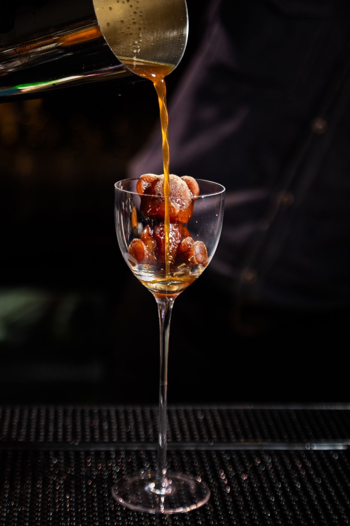 Coffee poured from a shaker over a bear-shaped ice mould in a tall glass