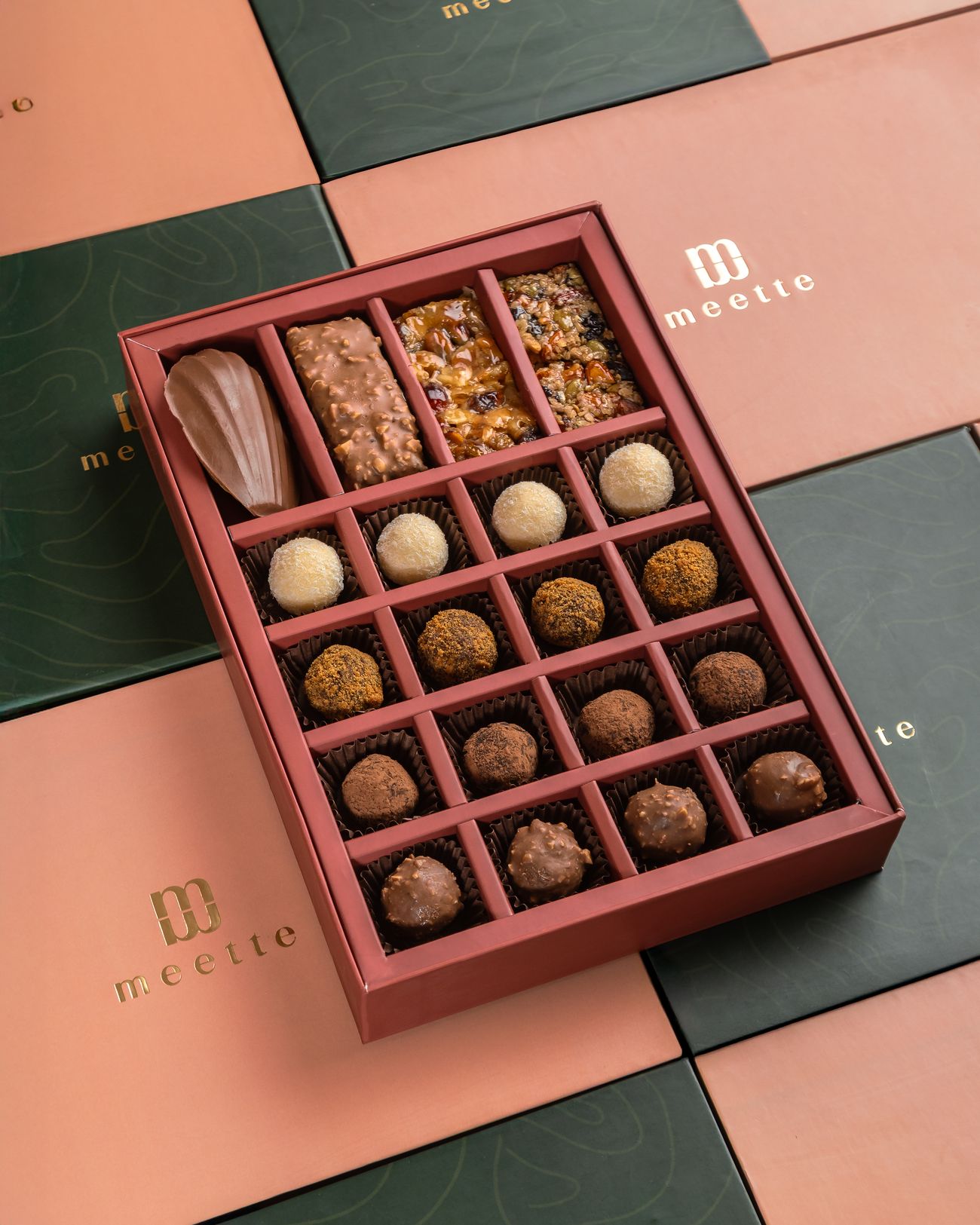 Open Meette gift box of chocolates and truffles on pink and green Meette boxes